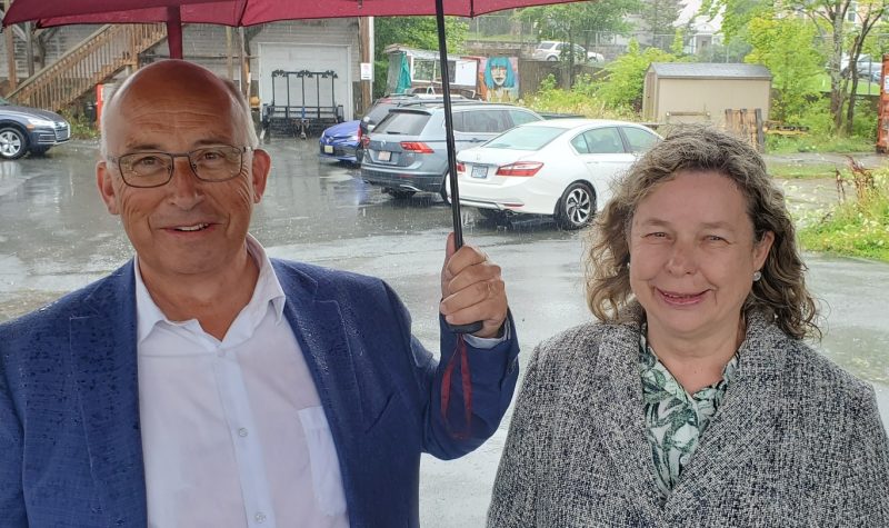 A man and a woman stand under an umbrella in the rain