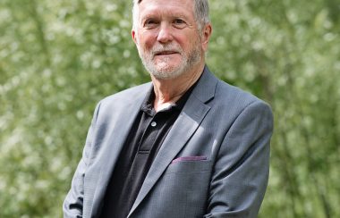 Pictured is Gerald Cutting in a grey suit with greenery serving as the background.