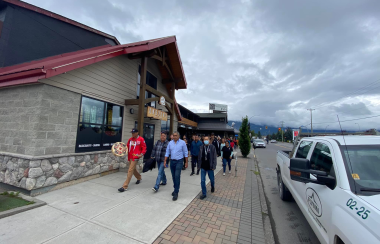 A group of people walking in front of a store, one with a traditional drum