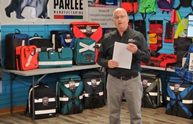 A man stands in front of a display of backpacks