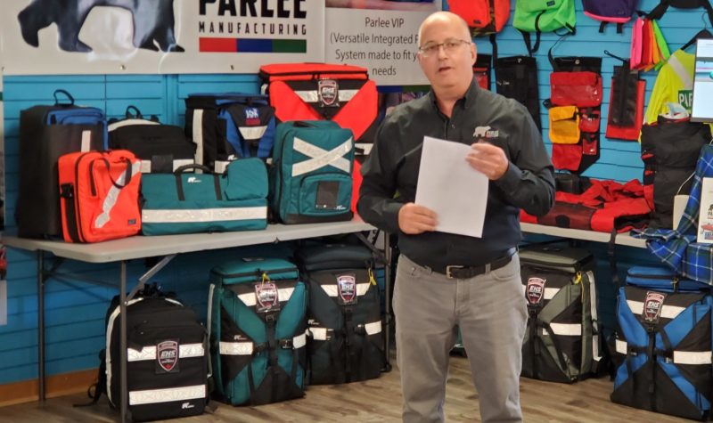A man stands in front of a display of backpacks