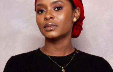 A woman in a black shirt with a red scarf in her hair.