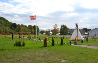 A photo of the Pontiac Native Community's healing garden in Mansfield, featuring a teepee, orange flag and plants arranged in a circle.