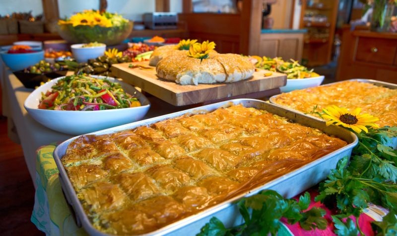 Fresh baking and vegetarian dishes are displayed on a buffet table, adorned with sunflowers.