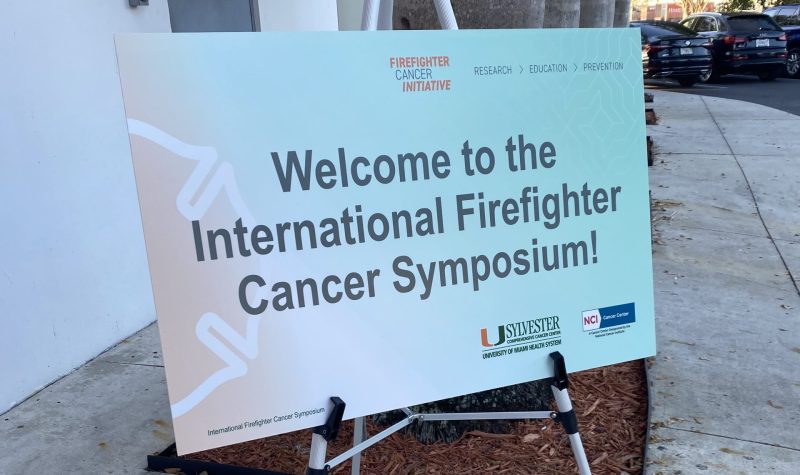An orange and green poster that says 'Welcome to the International Cancer Firefighter Symposium.