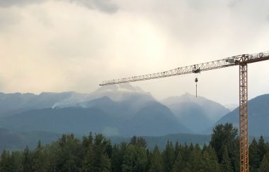 A plume of smoke rises from a mountain in the distance.