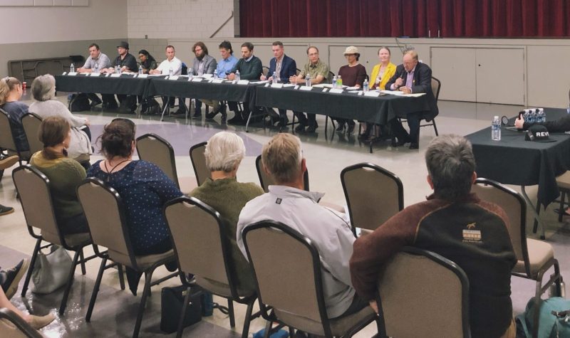 A room full of people sits before 12 people all at a table together.