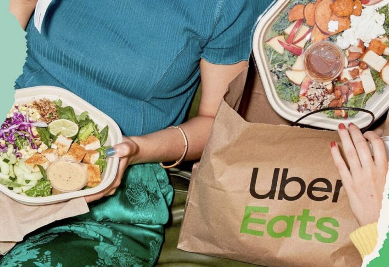 Une personne mange une salade alors qu'une deuxième sort une salade d'un sac Uber Eats.