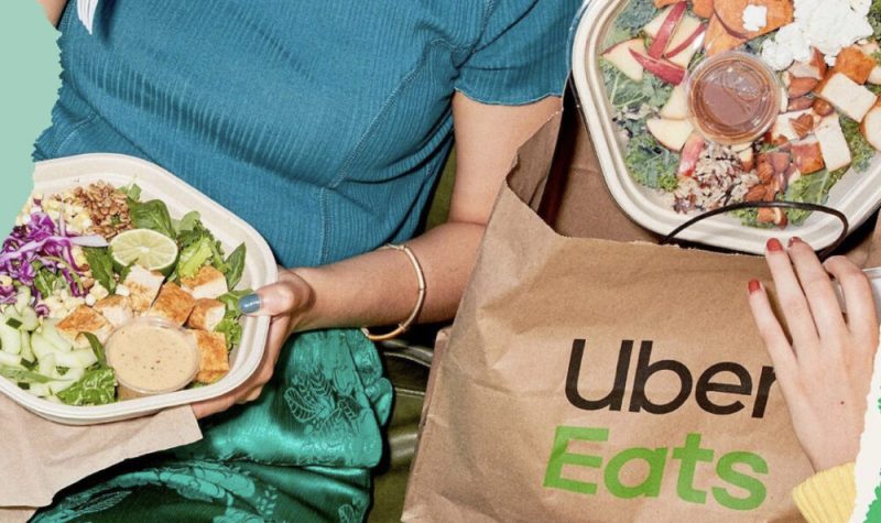 Une personne mange une salade alors qu'une deuxième sort une salade d'un sac Uber Eats.