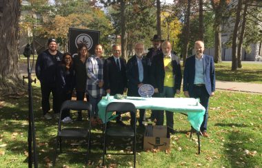 People stand outdoors behind a table