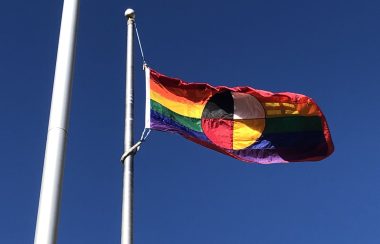 Un drapeau arc-en-ciel contient la roue médicinal autochtone au centre.