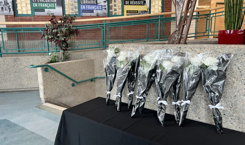 Des bouquets de fleurs sur une table couverte avec une nappe noire, des portraits alignés au mure derrière