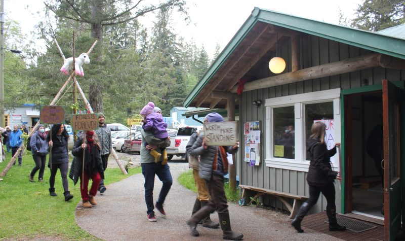 A lineup of protesters holding signs march into a building.