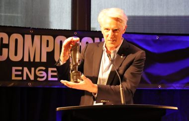 Image shows Allan Reid holding JUNO Award at event on stage