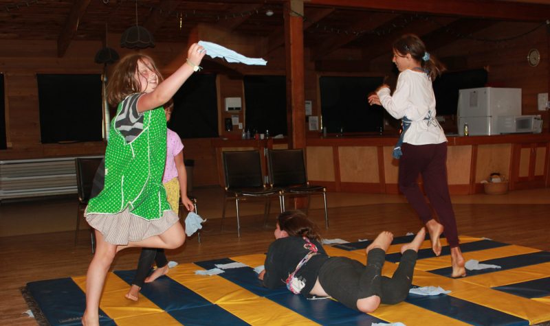 Youth perform a dance on a yellow and blue gym mat.