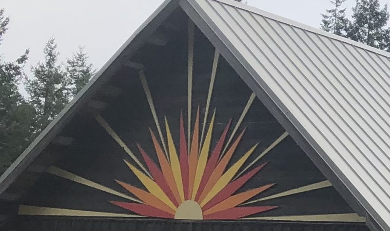 Sunburst colours of yellow, red and orange adorn an outdoor peaked roof at Mansons Landing community hall.