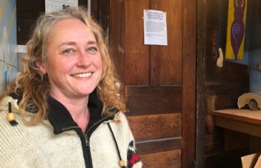 The executive director of the Cortes Island Women's Resource Centre sits outside the entrance to the facility.