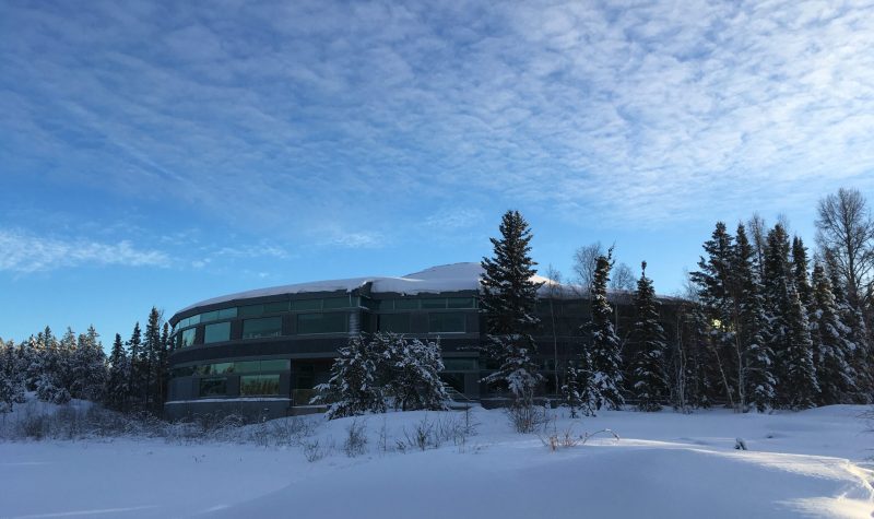 Le dome de l'Assemblé législative des TNO se dresse derrière les sapins, en hiver.