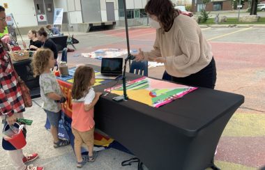 Une intervenante de l'organisme Freeze Frame montre un jeu d'animation en « step motion» à des enfants sous un kiosque en plein air.