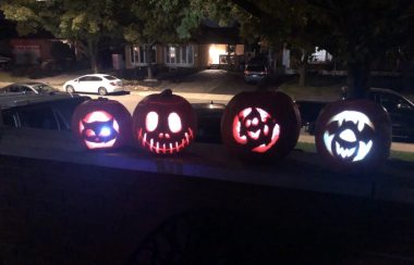 Four carved pumpkins sit on a ledge.