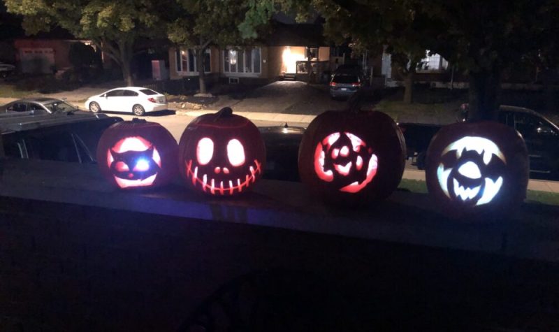 Four carved pumpkins sit on a ledge.