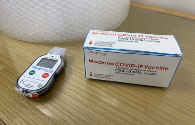 Une boite contenant le vaccin Moderna, et un appareil servant à en contrôler la température