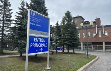 Une pancarte bleue avec le nom de l'établissement devant un bâtiment brun