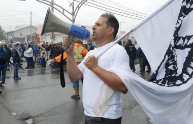 Un homme en t-shirt blanc avec un drapeau à la main et un haut-parleur dans l'autre