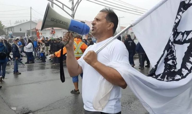 Un homme en t-shirt blanc avec un drapeau à la main et un haut-parleur dans l'autre