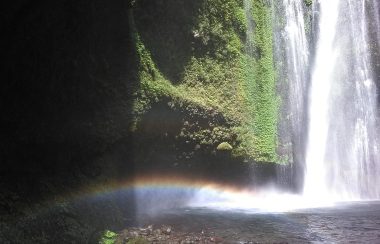 A rainbow is casted under a waterfall.