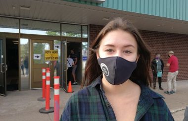 A photo of Sydney Thorburn outside a polling station at Mount Allison.