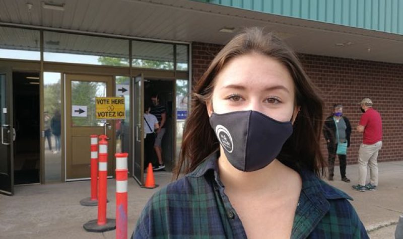 A photo of Sydney Thorburn outside a polling station at Mount Allison.