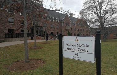 A building with circular driveway, trees in front, and sign reading Wallce McCain Student Centre, 62 York Street.