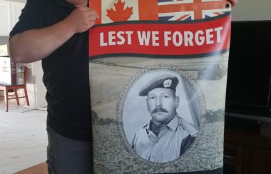 Garth Zwicker holds up the banner honouring his father, Eugene Zwicker, who was a veteran of the Korean War. The banner is one of 126 adorning light poles in Sackville each fall. Photo: Erica Butler