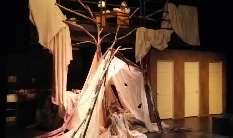 The set of a play, with trees amd blankets set up in a sort of fort