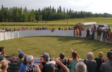 Une foule est amassée autour d'une arène circulaire, dans laquelle se trouve six participants.