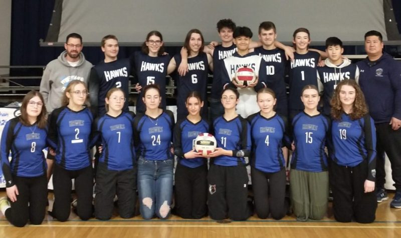 Des jeunes en uniformes de sport posent pour une photo, avec leurs entraîneurs à leurs côtés.