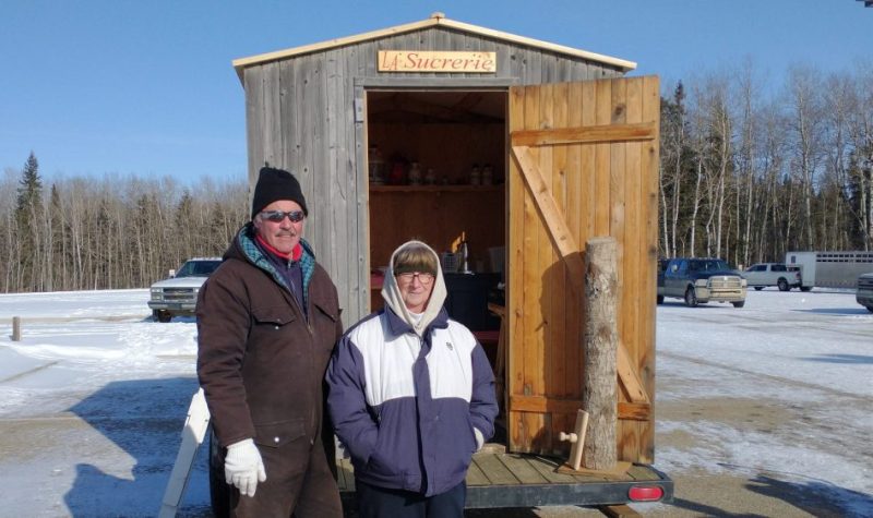 Leonard et Annette Lemay posent devant leur cabane à sucre mobile, à l'extérieur.