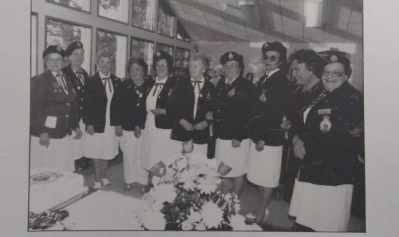 Une photo en noir et blanc de dix femmes habillés de vestons et de jupes, avec des chapeaux militaires. Sous la photo est inscrit « 25th anniversary of Ladies Auxiliary »