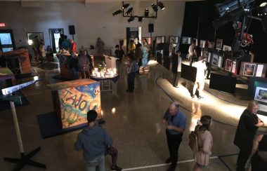 Des gens dans une salle tamisé entouré de photo et de maquette