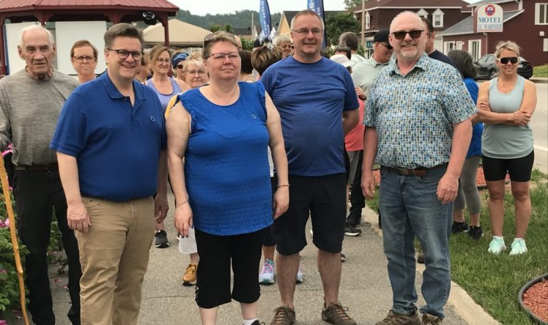 L'organisation de la marche habillée en bleu prenant la pose avec les participants en arrière-plan