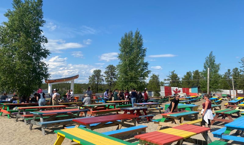 Des dizaines de tables de pique-nique multicolores sont aménagées sur le site du festival Folk on the Rocks.