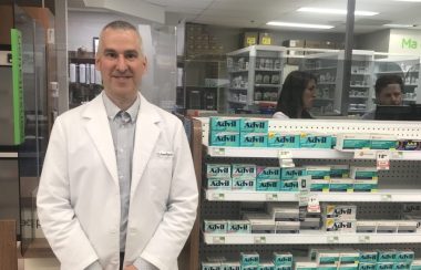 Un pharmacien debout devant son comptoir