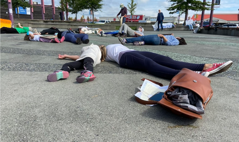 Half a dozen people lay sprawled across a the tiles of a city squre