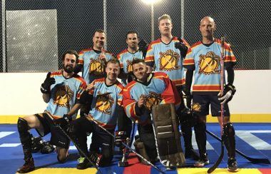 Sept personnes dans une photo d'équipe de hockey en équipement sur une surface bleue