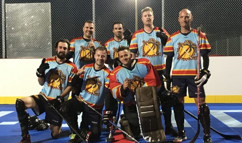 Sept personnes dans une photo d'équipe de hockey en équipement sur une surface bleue