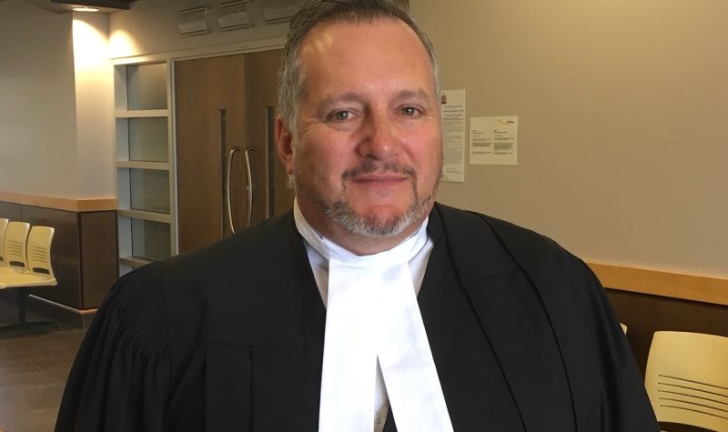 A man in lawyer's robes standing in hallway.