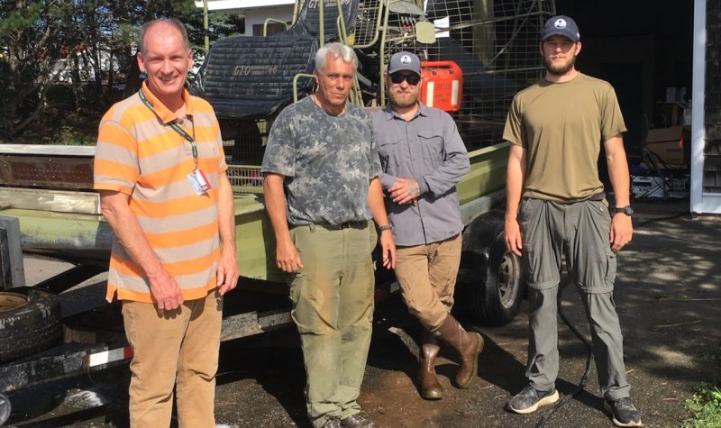 A group of four men standing in front of an airboat.