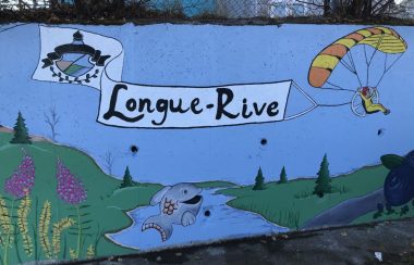 Un long dessin peinturé sur un mur de brique indiquant la mention Longue-Rive