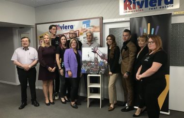 Neuf personnes prenant la pose autour du visuel de la tyrolienne.